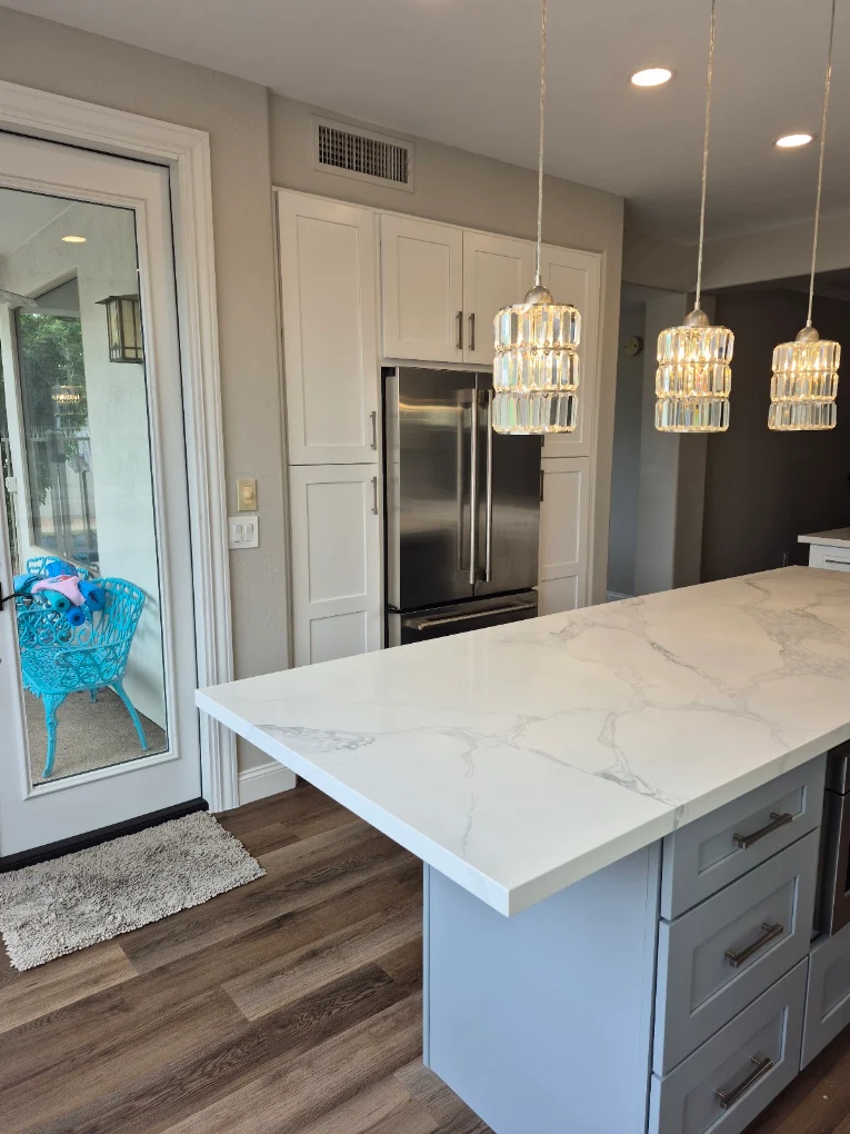 Remodeled kitchen island with light gray cabinetry and quartz countertop