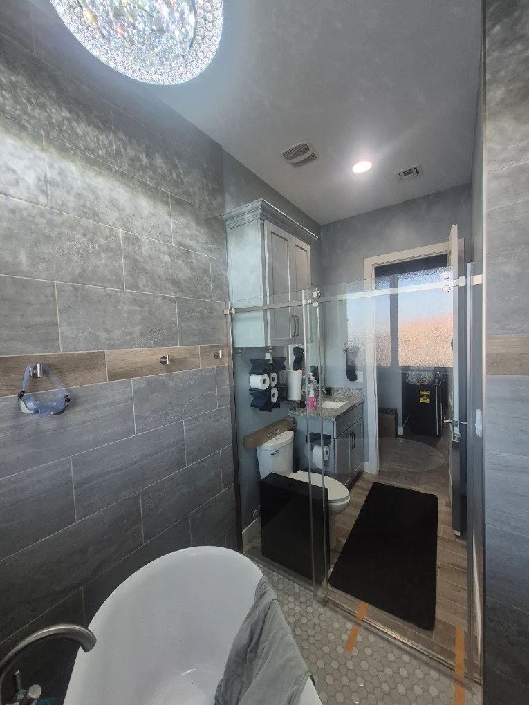 Bathroom with a freestanding tub, gray tile, and a wood-look accent band