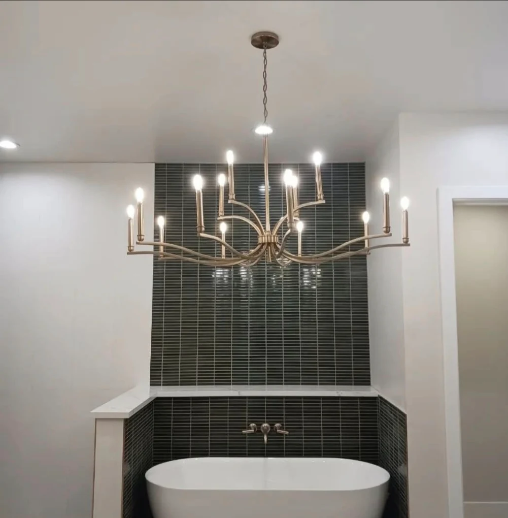 Finished bathroom with freestanding tub, dark tile surround, and chandelier