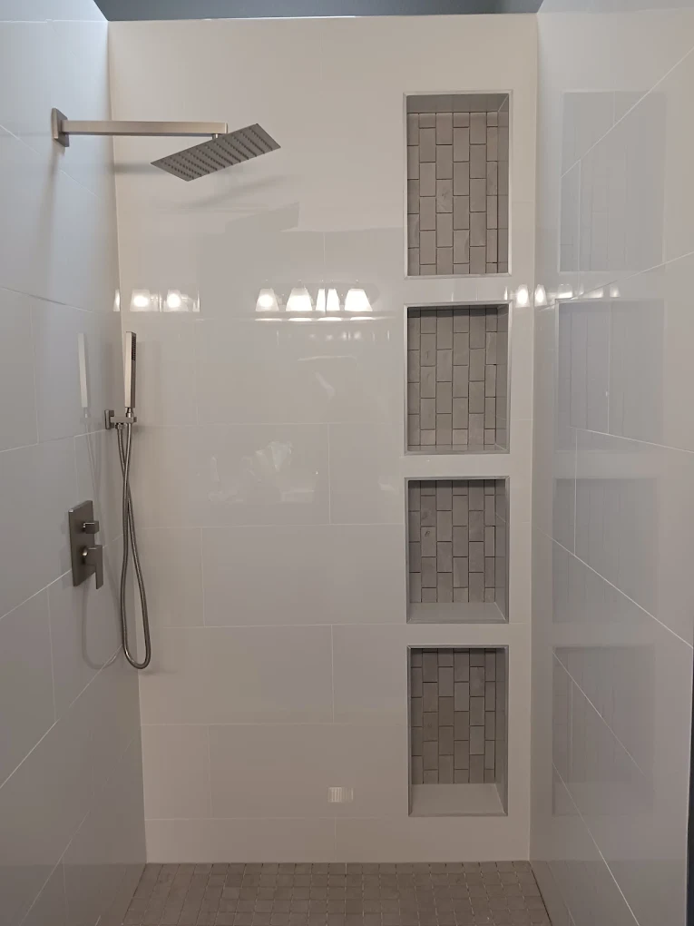 Finished white tile shower with four stacked recessed niches and brushed nickel fixtures