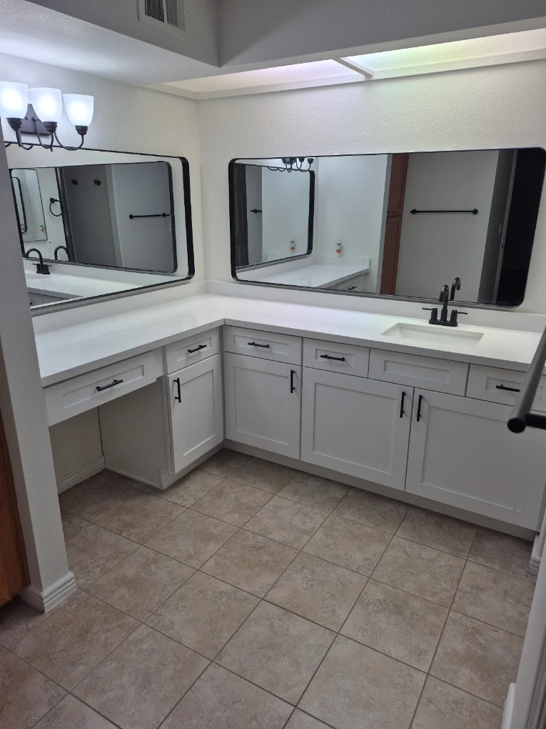 Remodeled bathroom vanity with white shaker cabinets and quartz countertop